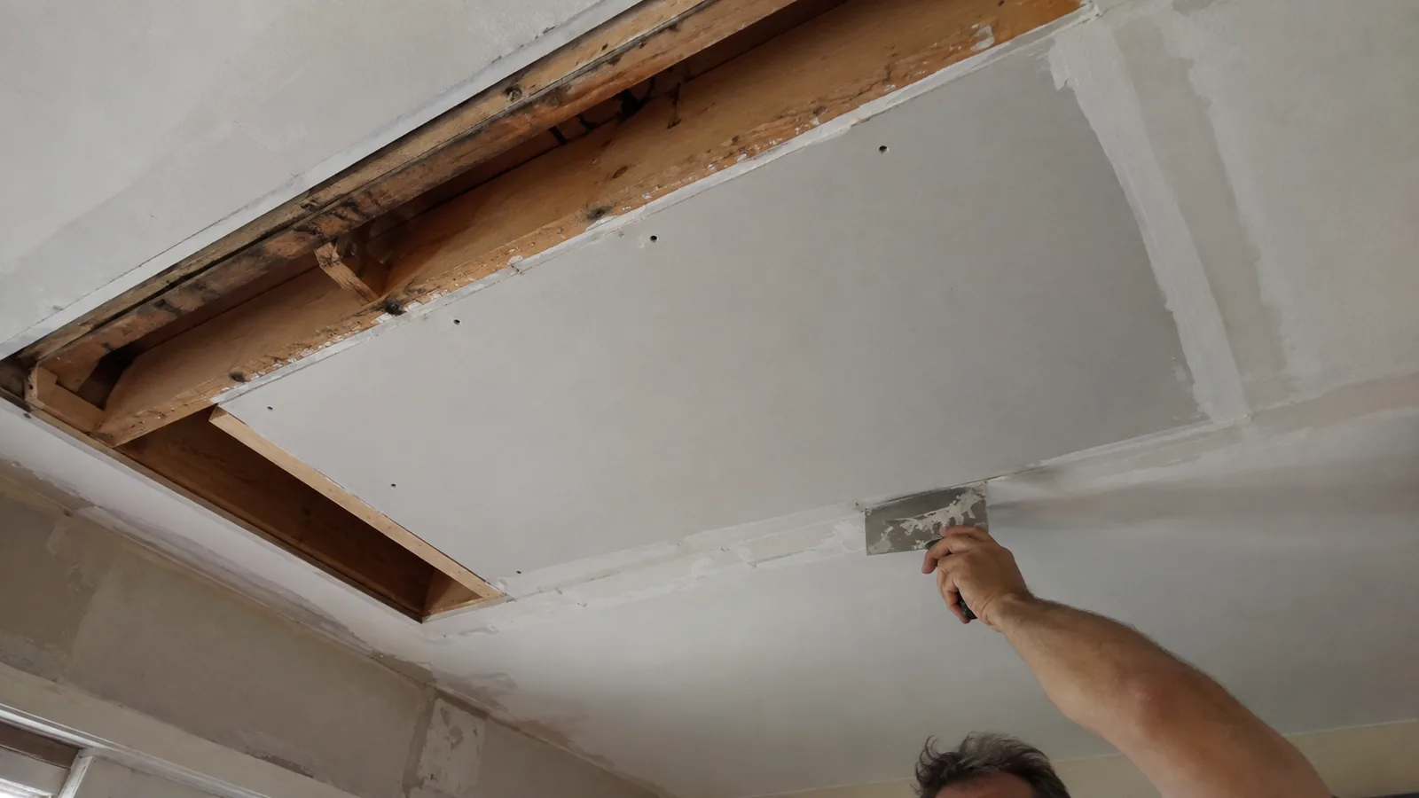 Cut-out section of a residential ceiling in Arvada, CO with a new gypsum board patch fitted between the joists