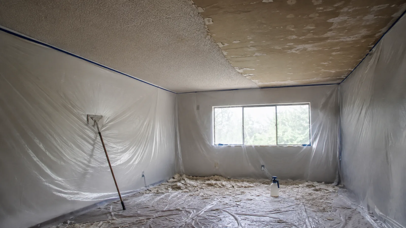 Popcorn ceiling half scraped in an Arvada, CO home with plastic sheeting taped floor to ceiling