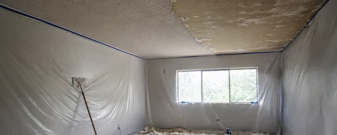 Popcorn ceiling half scraped in an Arvada, CO home with plastic sheeting taped floor to ceiling