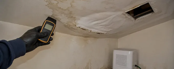 Water stained and sagging drywall ceiling in an Arvada, CO home with a moisture meter being used at the opening