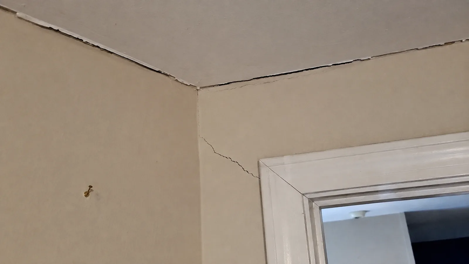 Separation crack along the wall and ceiling junction in an Arvada, CO home, with a second crack from a door corner