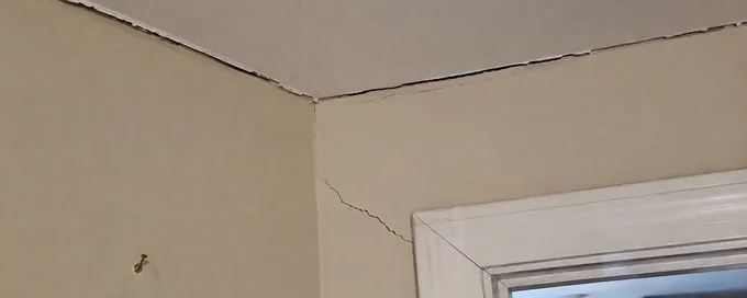 Separation crack along the wall and ceiling junction in an Arvada, CO home, with a second crack from a door corner